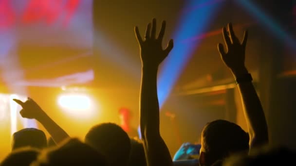 Siluetas de personas festejando en el concierto de rock frente al escenario - cámara lenta - Imágenes, Vídeo