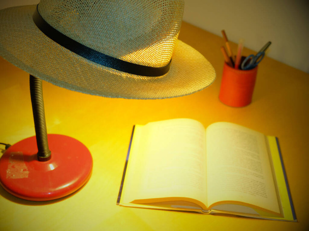 lampa stołowa z kapeluszem Panama na górze oświetla książkę - Zdjęcie, obraz