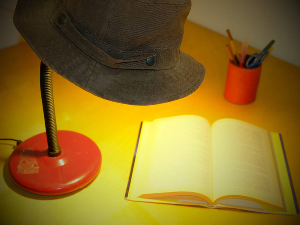 stolní lampa s kovbojským kloboukem spočívajícím na vrcholu osvětluje knihu - Fotografie, Obrázek