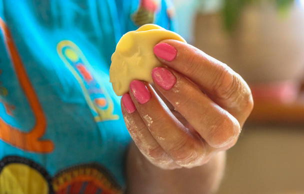 Una bola de masa en las manos de las mujeres. El proceso de hacer albóndigas tradicionales caseras. Modelado de deliciosos varenyki, pelmeni, ravioli, dumplings. - Foto, Imagen
