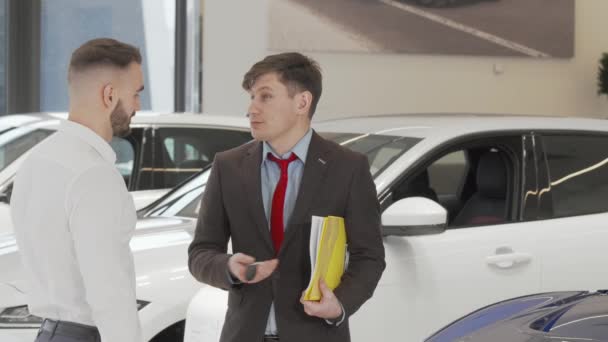 Cheerful car dealer apertando as mãos com um cliente depois de dar-lhe chaves do carro - Filmagem, Vídeo