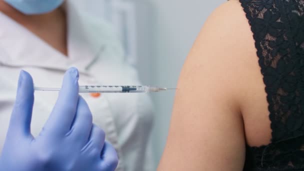 Vakcína COVID-19. Zdravotní sestra, která podává pacientovi na klinice očkovací látku. Doktor používá podkožní jehlu a injekční stříkačku k aplikaci léků jako léčbu. - Záběry, video