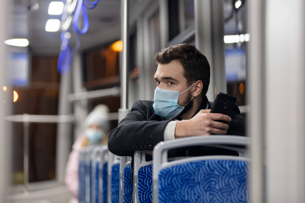 Einsamer Mann mit Gesichtsmaske fährt nachts in Polen in der Straßenbahn - Foto, Bild
