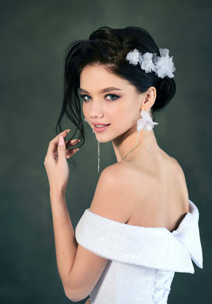 Beautiful smiling bride with wedding makeup and fashion hairstyle. Gorgeous young woman in a white dress with a jewelry in her hair - Fotó, kép