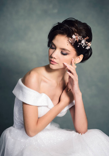 Beautiful bride with fashion hairstyle. Gorgeous young woman in a white dress with a jewelry in her hair - Fotografie, Obrázek