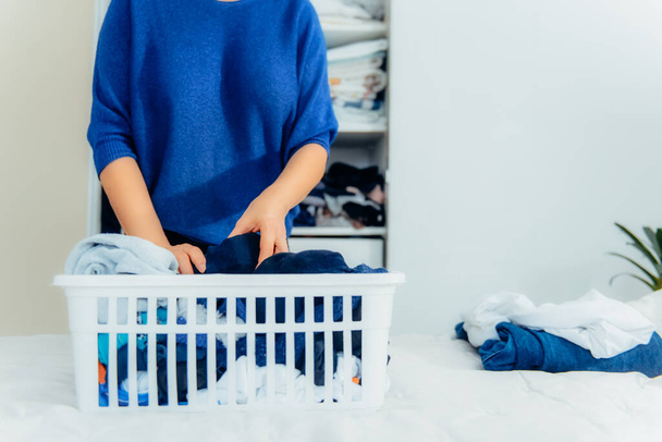 Woman putting male socks into container basket. Organizing wardrobe drawers during general cleaning by the modern storage system. Concept of comfortable home space organization. Selective focus. - Photo, Image