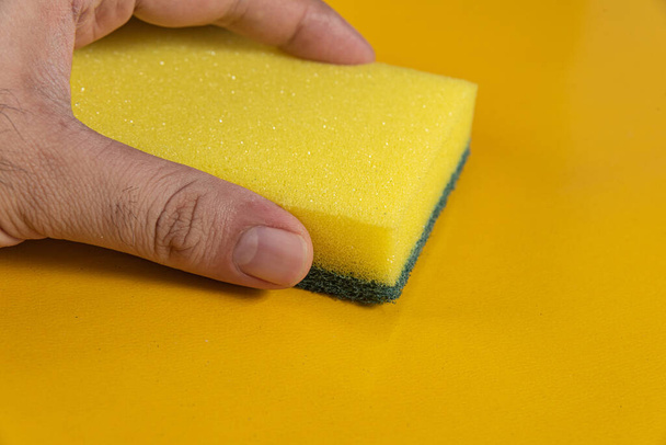 Man holding kitchen sponge on the yellow background - Photo, Image