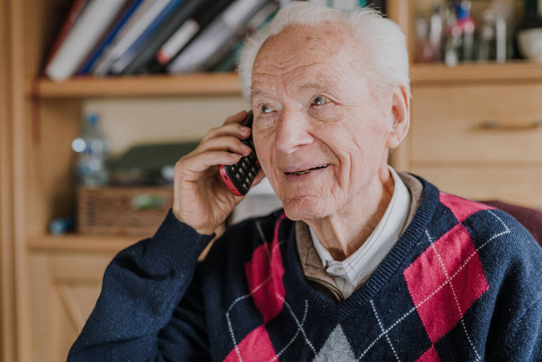 Starší muž mluví po telefonu, sedí doma - Fotografie, Obrázek