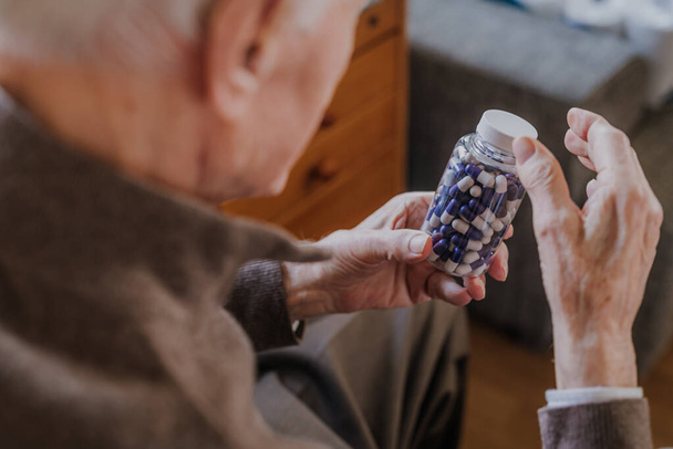 Senior hält Flasche mit Pillen in Nahaufnahme - Foto, Bild