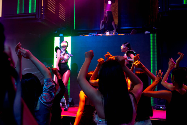 Grupa ludzi tańczy w klubie nocnym disco do rytmu muzyki DJ na scenie - Zdjęcie, obraz