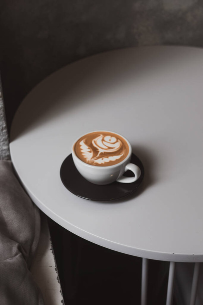 Plochá bílá káva, květinové latté na bílém stole, koncept hipsterské kavárny. Minimalistické pozadí, kopírovací prostor. Shora - Fotografie, Obrázek
