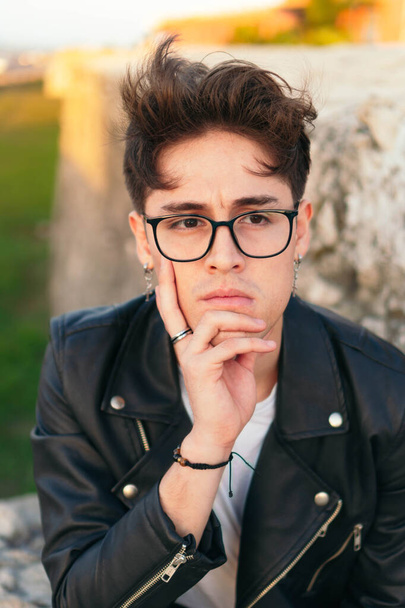 Young man in casual clothes and glasses sad. Sitting looking to the side - Fotoğraf, Görsel