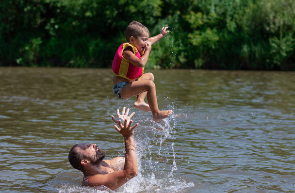 Πατέρας και γιος κολυμπάνε και πηδάνε στο νερό. - Φωτογραφία, εικόνα