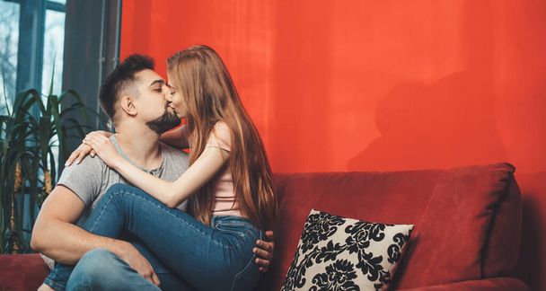 homme caucasien tenant sa femme roux sur les jambes et l'embrasser célébrer ensemble la Saint-Valentin - Photo, image