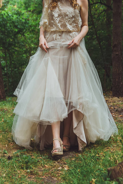 nevěsta drží spodní části svatebních šatů a ukazuje boty - Fotografie, Obrázek