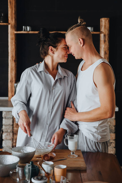 Young couple in love cook healthy food in the kitchen together. While laughing and talking. - Photo, Image