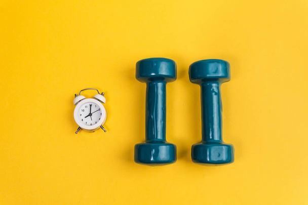 Dumbbell alarm clocks on a yellow background. Morning sports. sport concept background - Foto, Bild