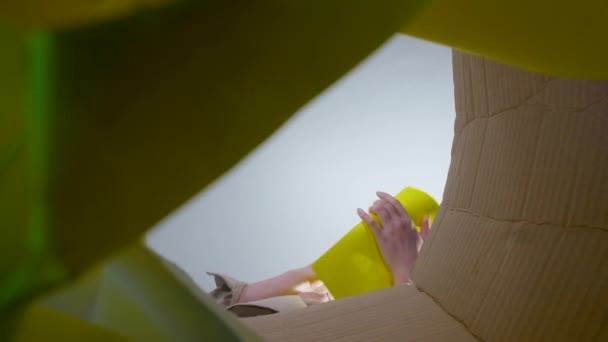 Стрельба женщины бросает мятую желтую бумагу, вид снизу - Кадры, видео