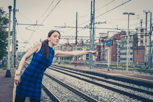 Pretty girl hitchhiking along the tracks  - Foto, afbeelding