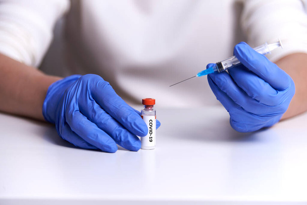 ο γιατρός λαμβάνει το εμβόλιο με μια σύριγγα για ένεση από δοκιμαστικό σωλήνα. Εμβολιασμός στο πλαίσιο πανδημίας - Φωτογραφία, εικόνα
