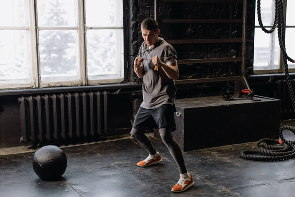 Крутой боец в боксерских повязках тренируется в спортзале. Смешанные боевые искусства - Фото, изображение