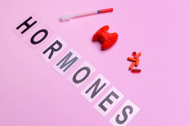 Parola ORMONI, ghiandola tiroidea, pillole e siringa su sfondo colore - Foto, immagini