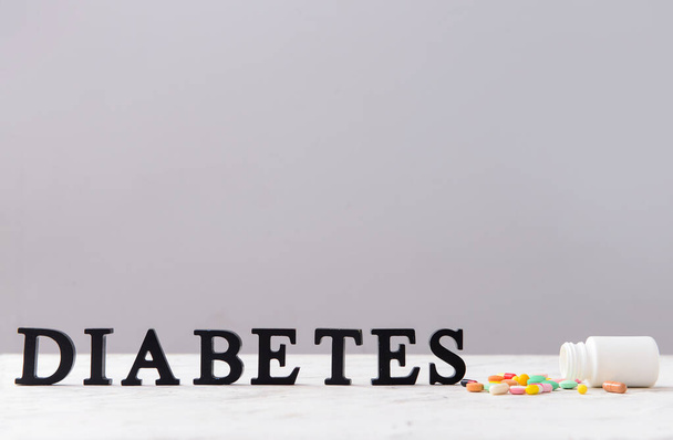Slovo DIABETES a pilulky na stole - Fotografie, Obrázek