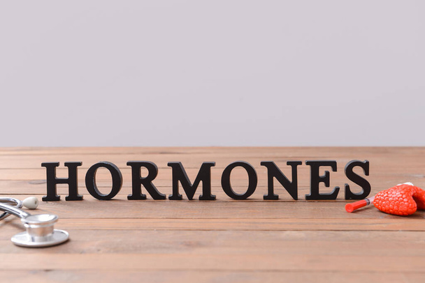 Ορμόνες λέξης, θυρεοειδής αδένας και στηθοσκόπιο σε ξύλινο τραπέζι - Φωτογραφία, εικόνα