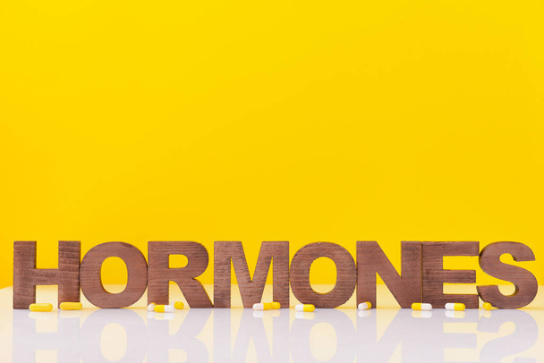 Word HORMONES et pilules sur la table sur fond de couleur - Photo, image