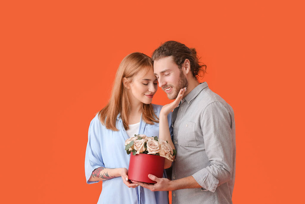 背景色に花を持つ若いカップル。バレンタインデーのお祝い - 写真・画像