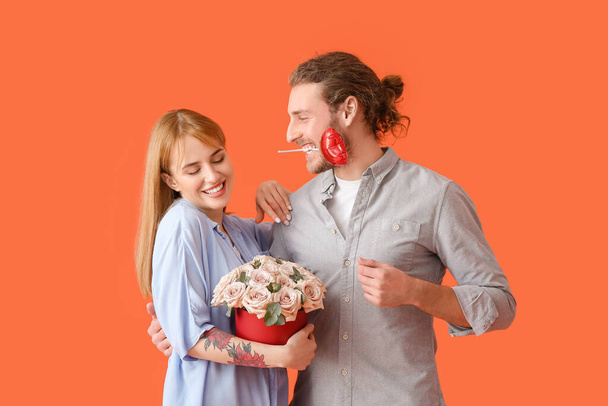Молодая пара с цветами и воздушным шаром на цветном фоне. Празднование Дня Святого Валентина - Фото, изображение