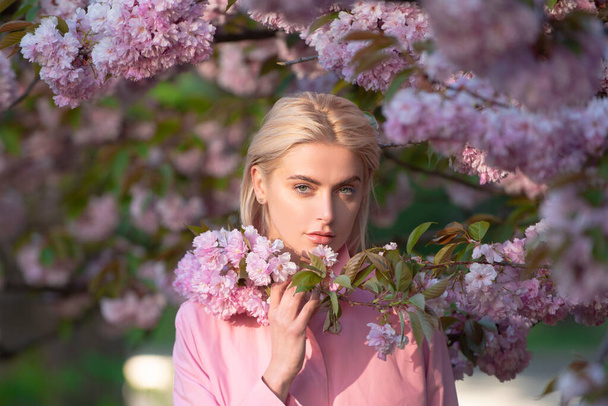 Girl in in blossoms cherry sakura. Outdoor portrait of beautiful sensual fashion girls posing near blooming tree with pink flowers. - Fotografie, Obrázek