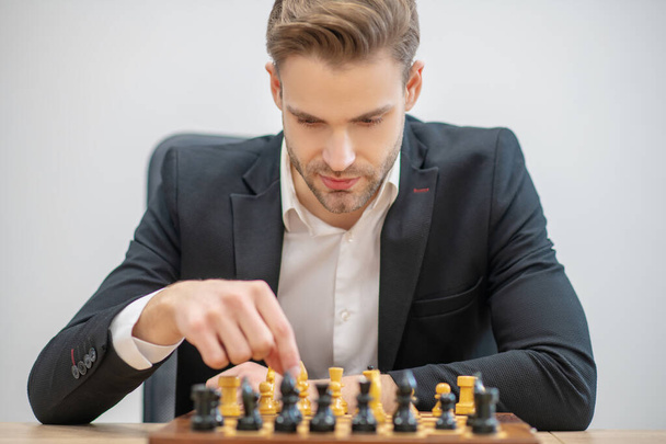 Young man placing chess pieces on chessboard - Foto, Imagen