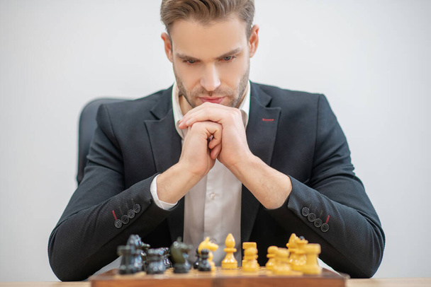 Serious involved man in front of chessboard - Φωτογραφία, εικόνα