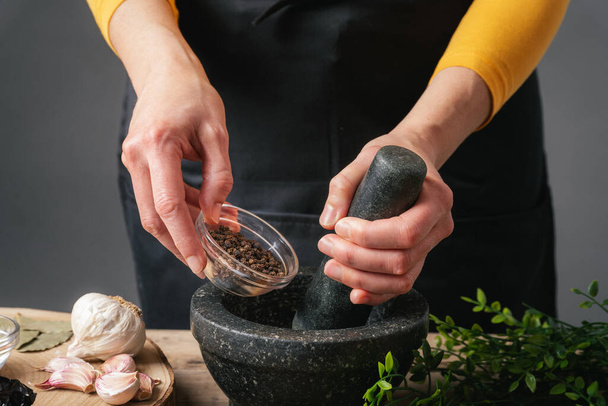 Woman hands pouring peppercorns into a mortar for grinding - Foto, Bild