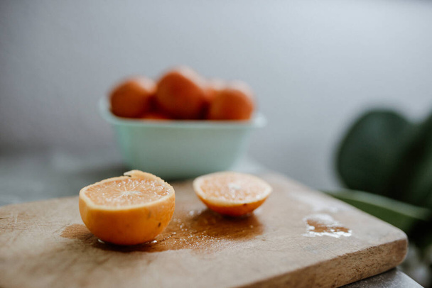 A closeup shot of a juicy cut orange on a wooden board - Foto, Imagem