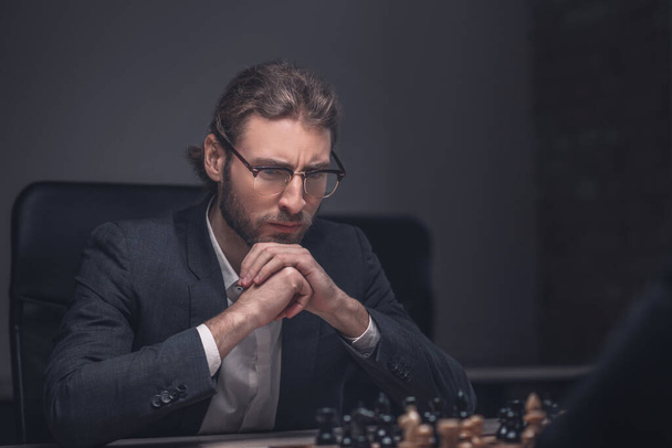 Serious man with glasses in front of chessboard - Photo, image