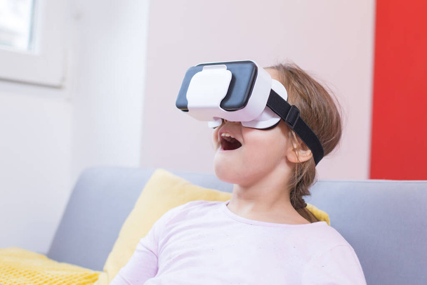 young girl using virtual reality goggles at home - Foto, Bild