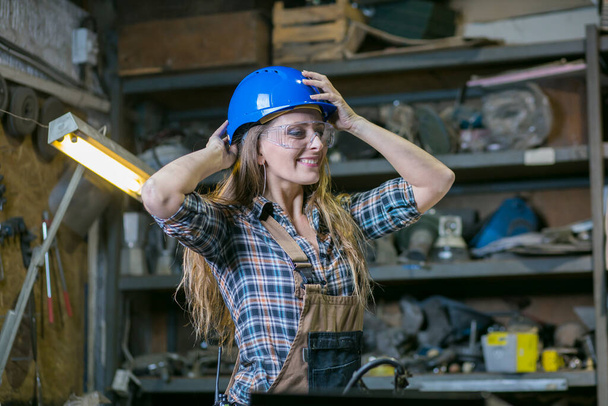 woman in workshop putting on protective helmet - Fotografie, Obrázek