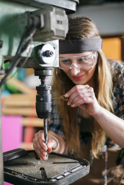 woman wearing safety glasses working in a metal workshop - Фото, изображение
