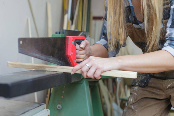 close up of a woman cutting wooden slat - Fotoğraf, Görsel