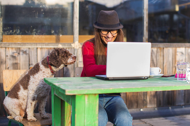 young woman working on laptop in company of her dog - Foto, afbeelding