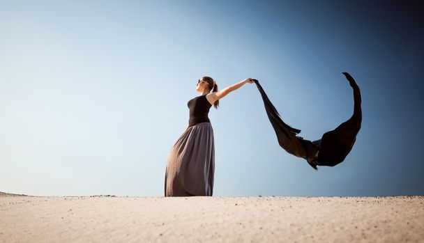 Arabska kobieta długo szmatką na pustyni w wietrzny dzień - Zdjęcie, obraz