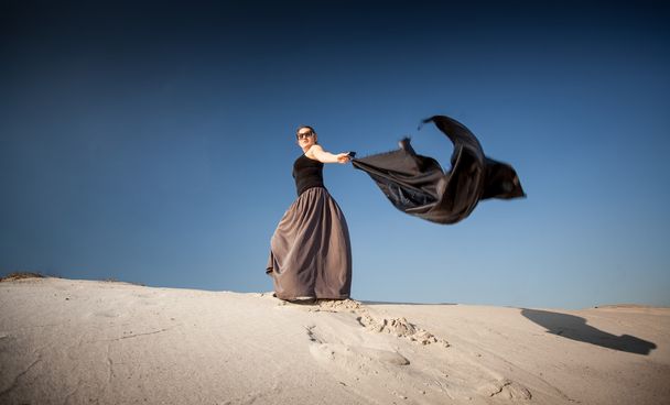 woman with black cloth walking on sand dunes - Fotoğraf, Görsel