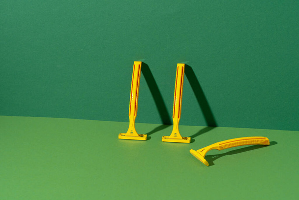 Disposable razor on green background, studio shot - Фото, изображение