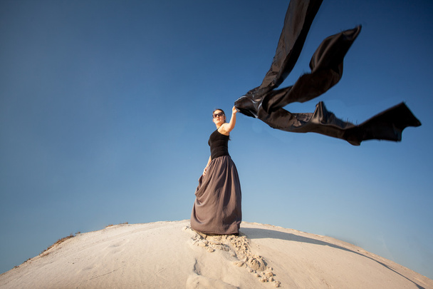 siyah kumaş rüzgarlı bir gün kumul üzerinde tutan kadın - Fotoğraf, Görsel