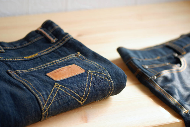 Τζιν παντελόνι στοιβάζονται σε ξύλινο φόντο με αντίγραφο χώρου για το σχεδιασμό κειμένου - Φωτογραφία, εικόνα