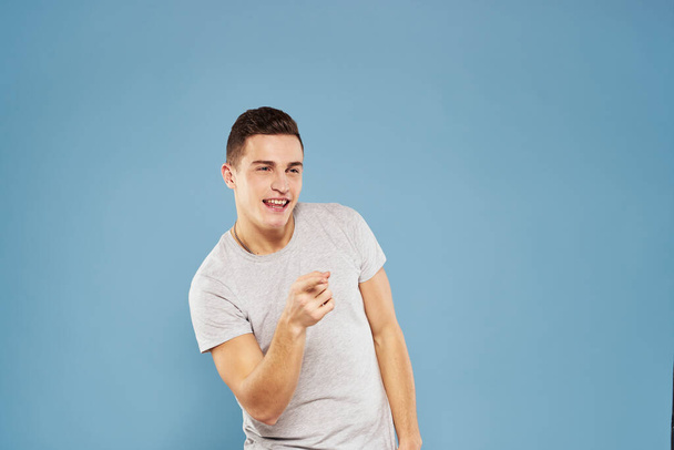 cheerful man in a white t-shirt gesturing with his hands emotions blue background - Φωτογραφία, εικόνα