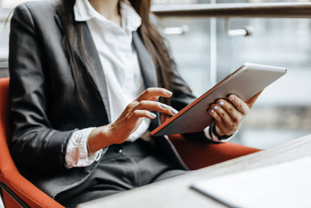 Businesswoman at her workplace reads information on a tablet. A woman works with documents and searches for insights on the Internet. The girl is thinking about the idea of a new startup in the office. - Foto, imagen