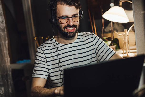 retrato de un joven que trabaja en casa en línea en el ordenador por la noche - Foto, Imagen